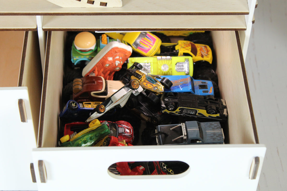 Hot Wheels cars arranged in a wooden garage — the environment that produces twenty minutes of quiet independent play