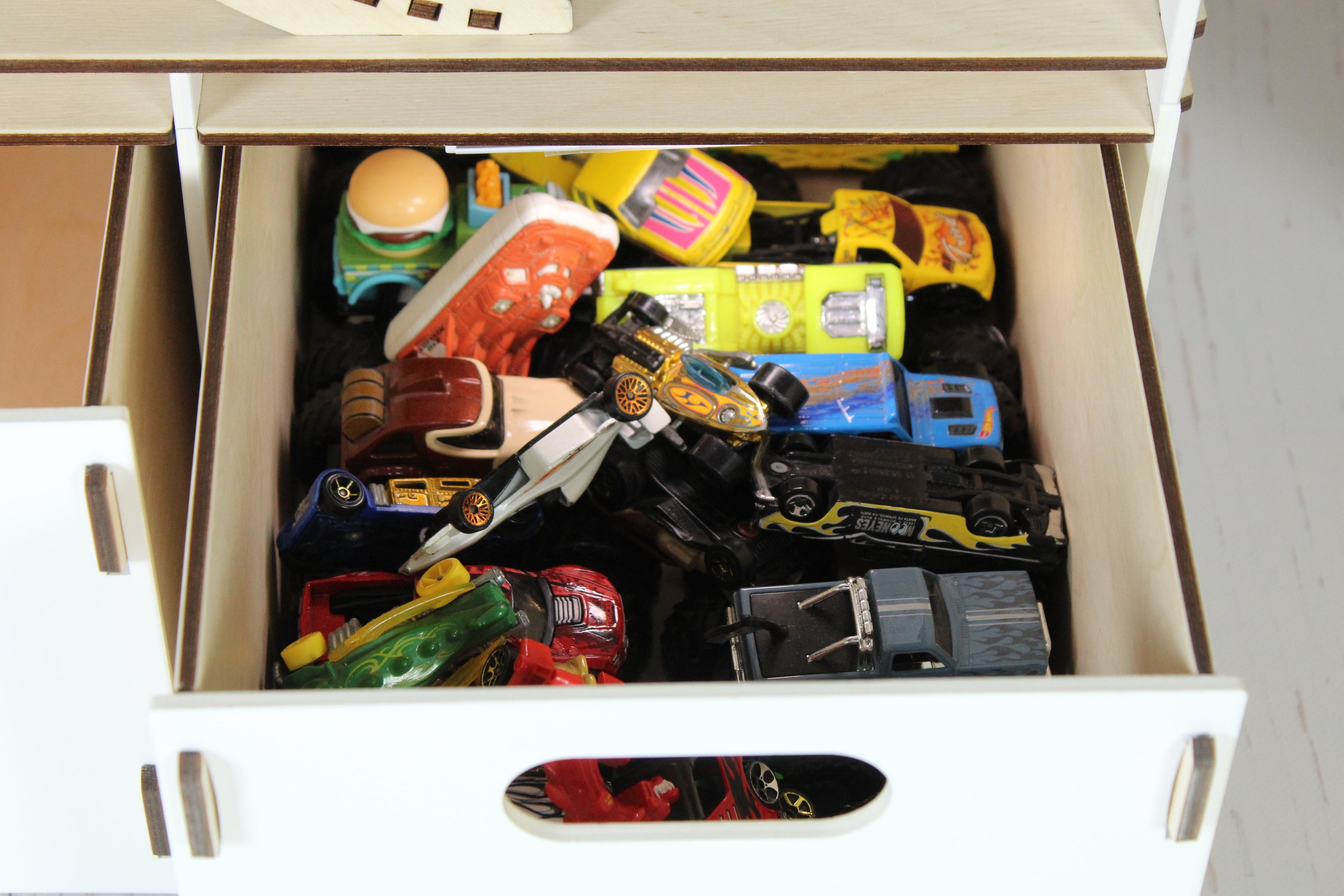 Hot Wheels cars organised in a personalized wooden toy car garage drawer