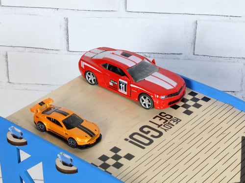Close-up of blue toy car ramp finish line with 1:64 diecast cars