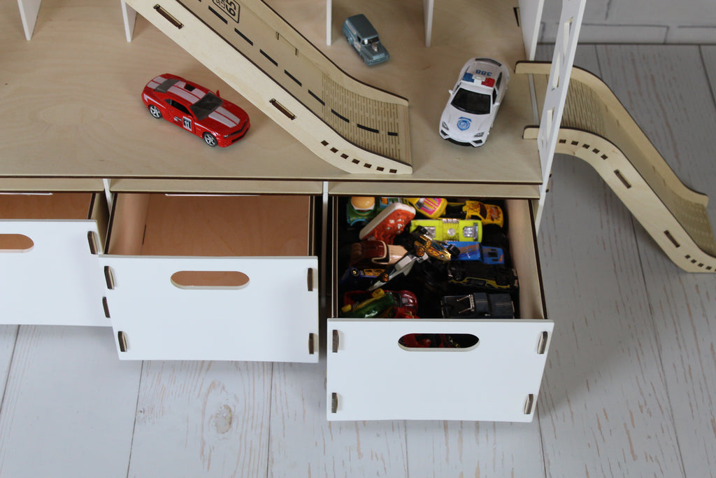 White wooden toy car garage with ramp, parking shelves and lower storage compartments