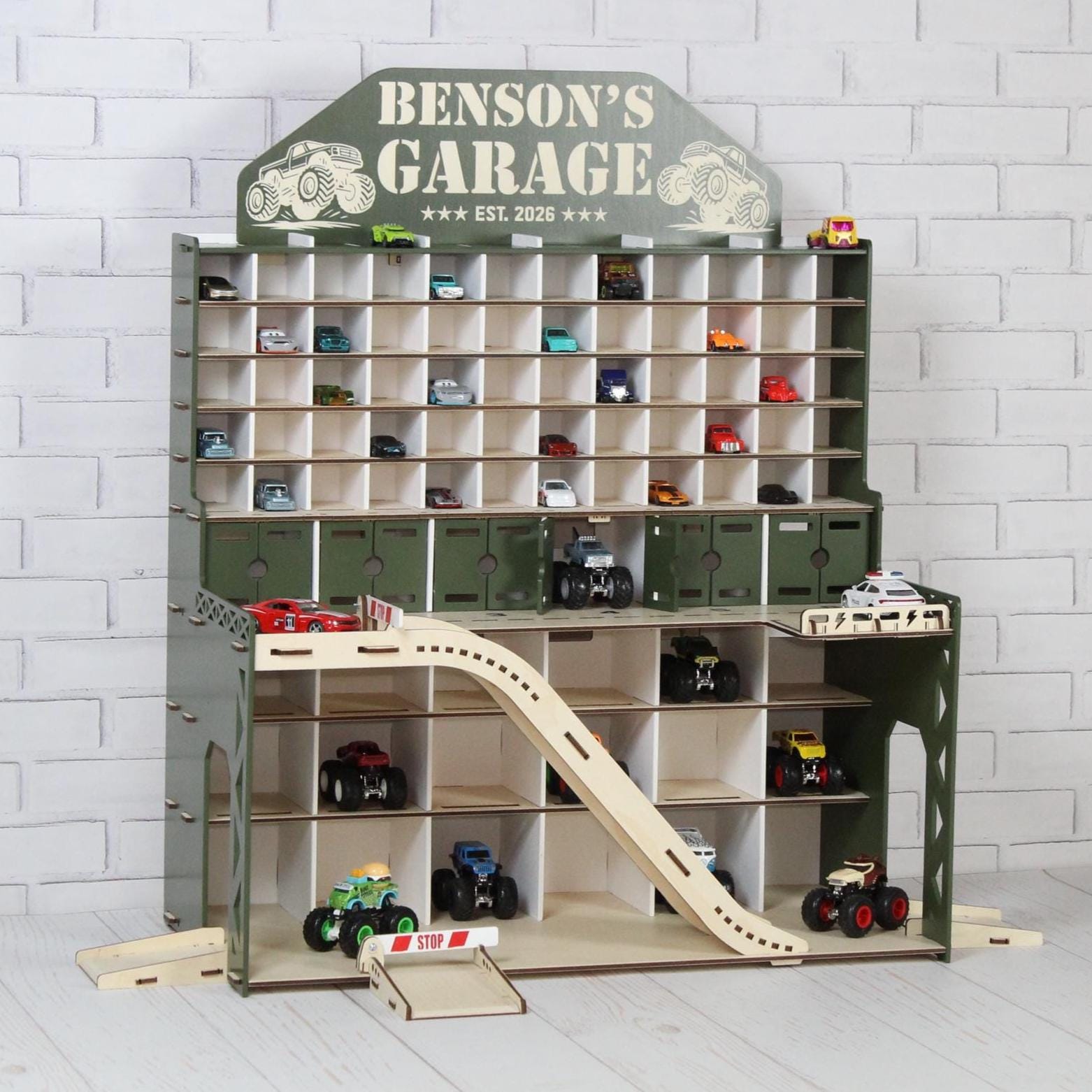 Side view of olive wooden toy car garage with ramp, shelves and Benson’s Garage nameplate